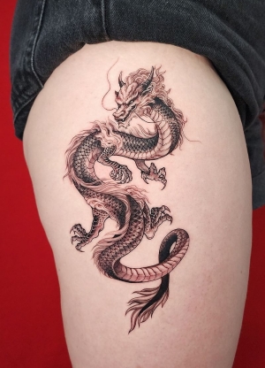 A beautiful flowy dragon tattoo on leg done at Dragon City Ink Da Nang.