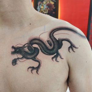 A cover-up tattoo with a fineline dragon on the shouder which done at Dragon City Ink Da Nang