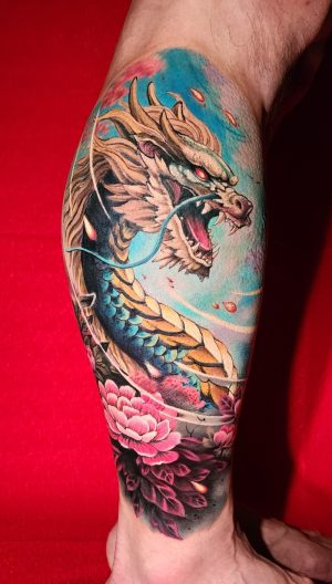 Semi realistic color dragon tattoo with peonies on leg at Dragon City Ink Da Nang.